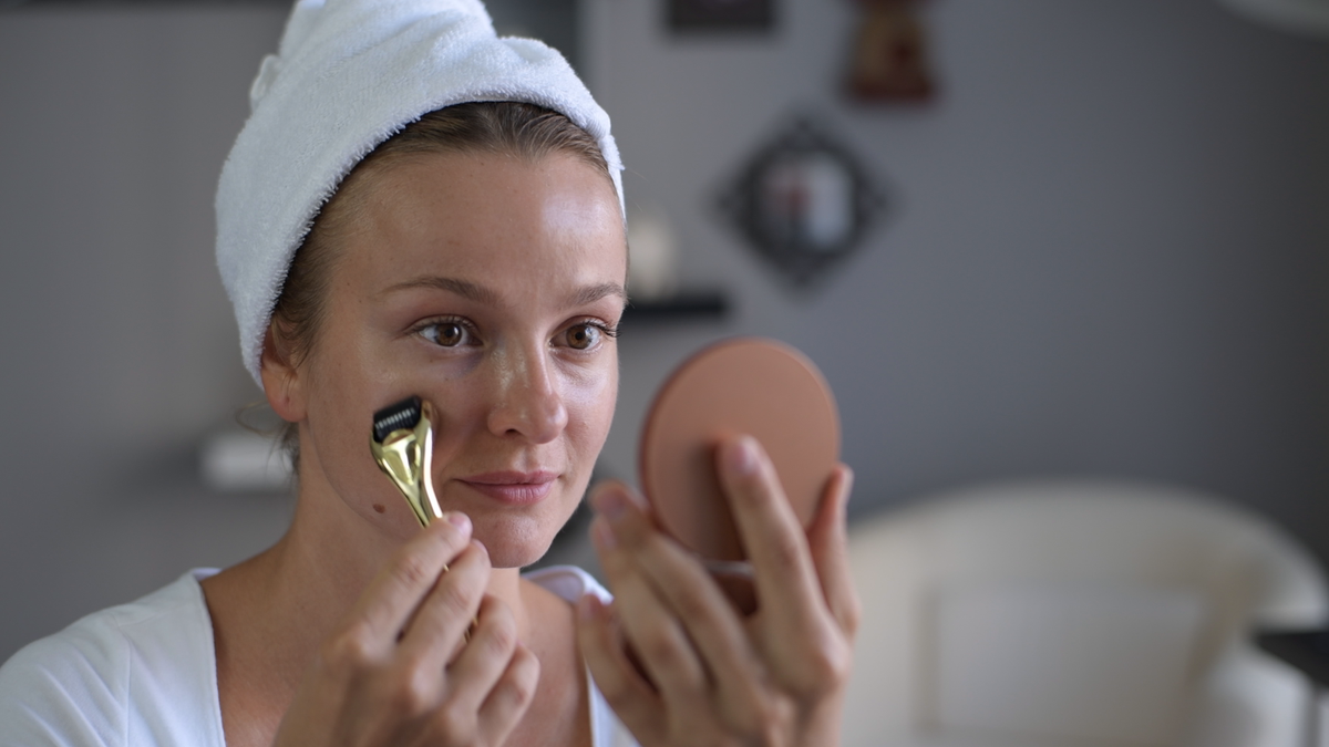Rolling the 1.5 mm derma roller along the cheek at a bathroom mirror